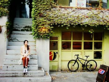 Full length portrait of woman sitting on bicycle in city