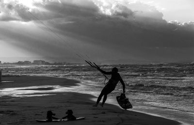Man kiteboarding at beach against sky