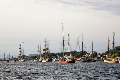 Sailboats moored at harbor against sky