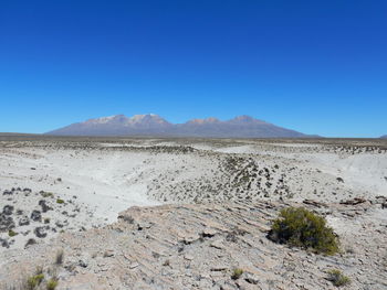 Scenic view of arid landscape against clear blue sky