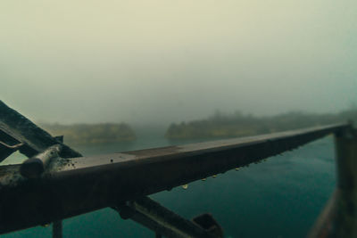 Close-up of railing by bridge against sky