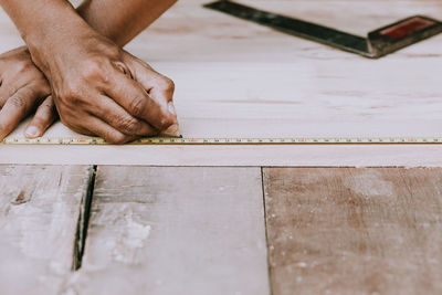 Cropped hands of carpenter measuring wood