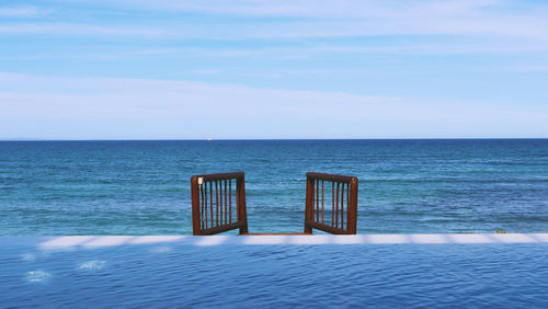 Chair on beach against sky