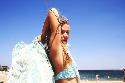 Portrait of beautiful young woman in sea against clear blue sky