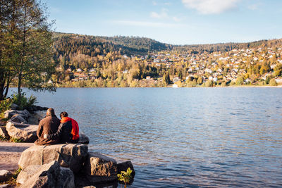 Couple sitting on rock at lakeshore