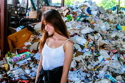 Young woman standing against garbage