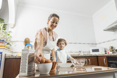 Low angle view of mother preparing food with son at home