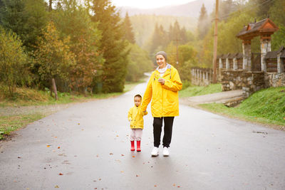 Rear view of mother and son on road