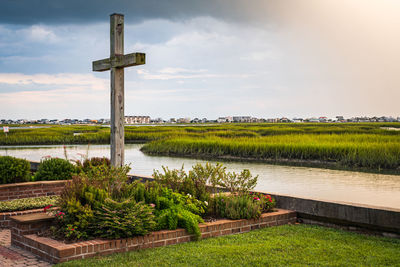 Built structure on field by lake against sky