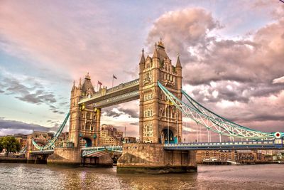 Tower bridge over river against cloudy sky during sunset