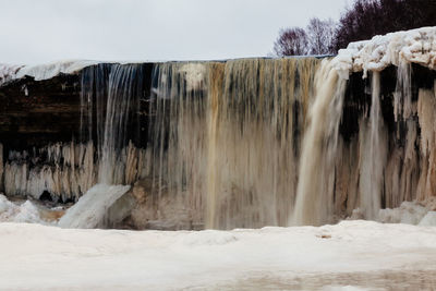 Scenic view of waterfall against sky during winter