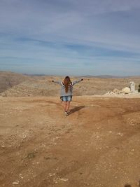 Full length of woman with arms raised against sky