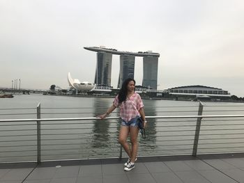 Woman standing by railing against sky