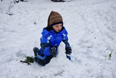 A boy sitting on snow covered land