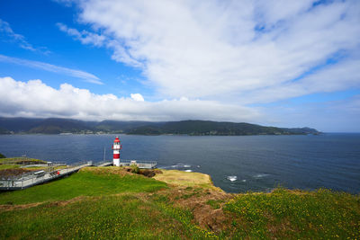 Lighthouse amidst sea and buildings against sky