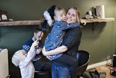 Portrait of happy female owner carrying daughter with family at eyeglasses workshop