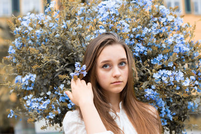 Portrait of young woman sitting against plants
