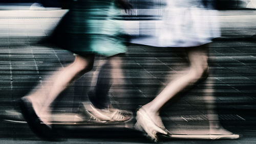 Low section of people walking on street in city