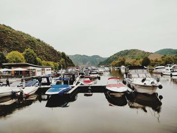 Boats moored at harbor against sky