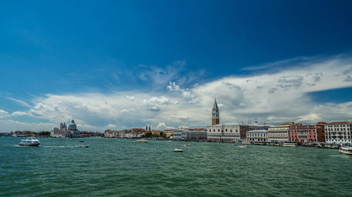 View of buildings by sea against cloudy sky