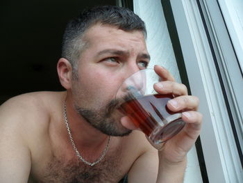 Shirtless man drinking rum at home