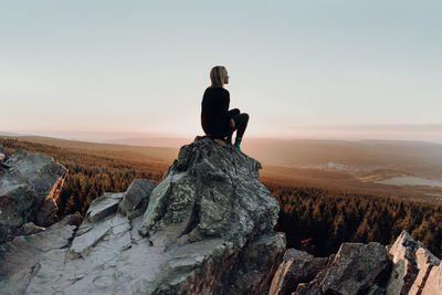 Woman sitting on rock against landscape