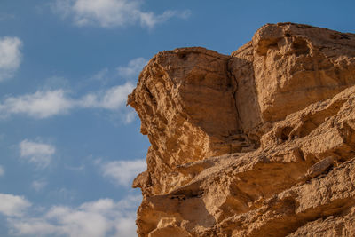 Low angle view of rocky mountains against blue sky