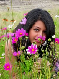 Portrait of young woman with pink flowers on field