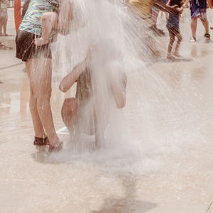High angle view of people enjoying splashing water at park during summer