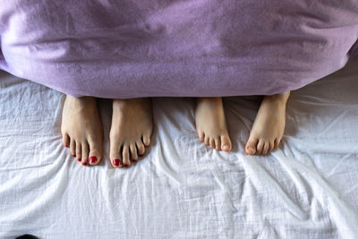 Low section of woman relaxing on bed