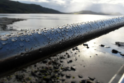 Close-up of wet railing at beach during sunset