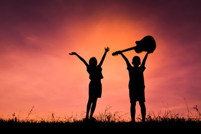 Silhouette children playing on field against sky during sunset