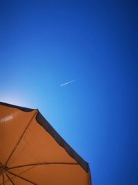 Low angle view of vapor trail against clear blue sky