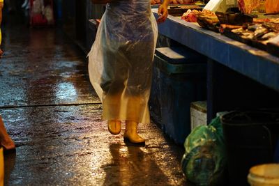 Low section of woman standing on wet table