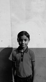 Portrait of boy standing against wall