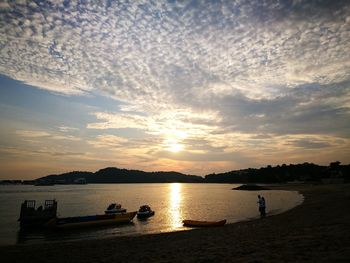 Silhouette of boats in water at sunset