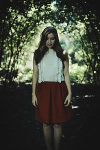 Beautiful young woman standing against tree