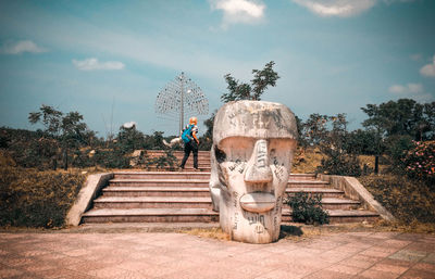 Statue by staircase against sky