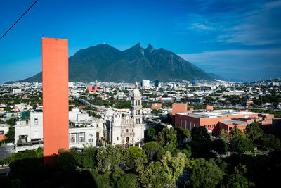 Panoramic view of townscape and mountains against blue sky