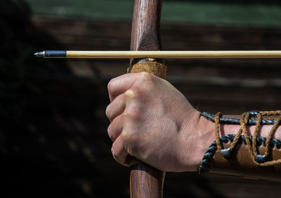 Cropped image of person aiming with bow and arrow