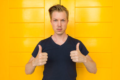 Portrait of man standing against yellow wall