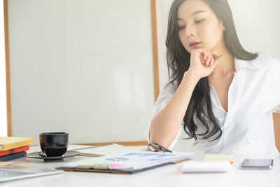 Young woman looking down while sitting on table