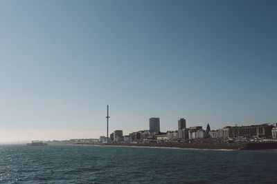 Scenic view of sea by buildings against clear sky on sunny day