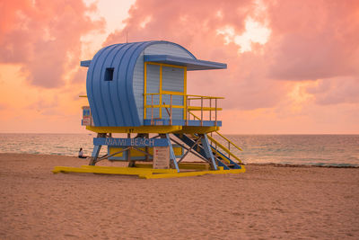 Lifeguard hut on beach against sky during sunset