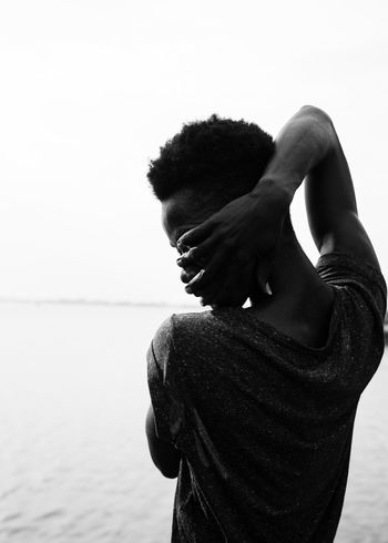 Silhouette young man dancing at beach against clear sky