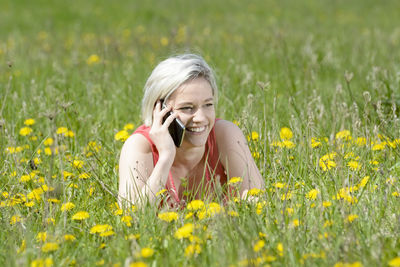 Portrait of smiling young woman with yellow flowers on field