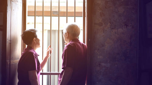 Side view of women standing by window