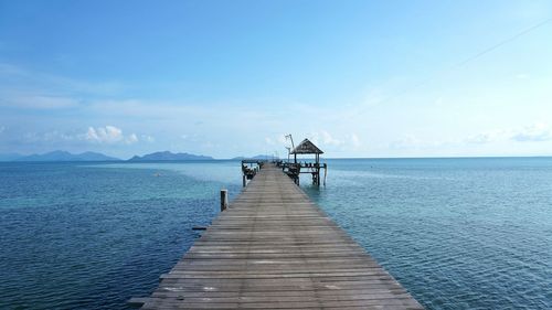 Pier over sea against clear blue sky