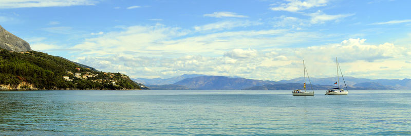 Sailboats in sea against sky