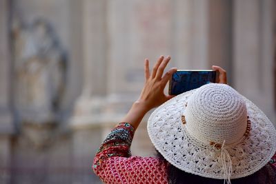 Rear view of woman wearing hat while photographing with mobile phone